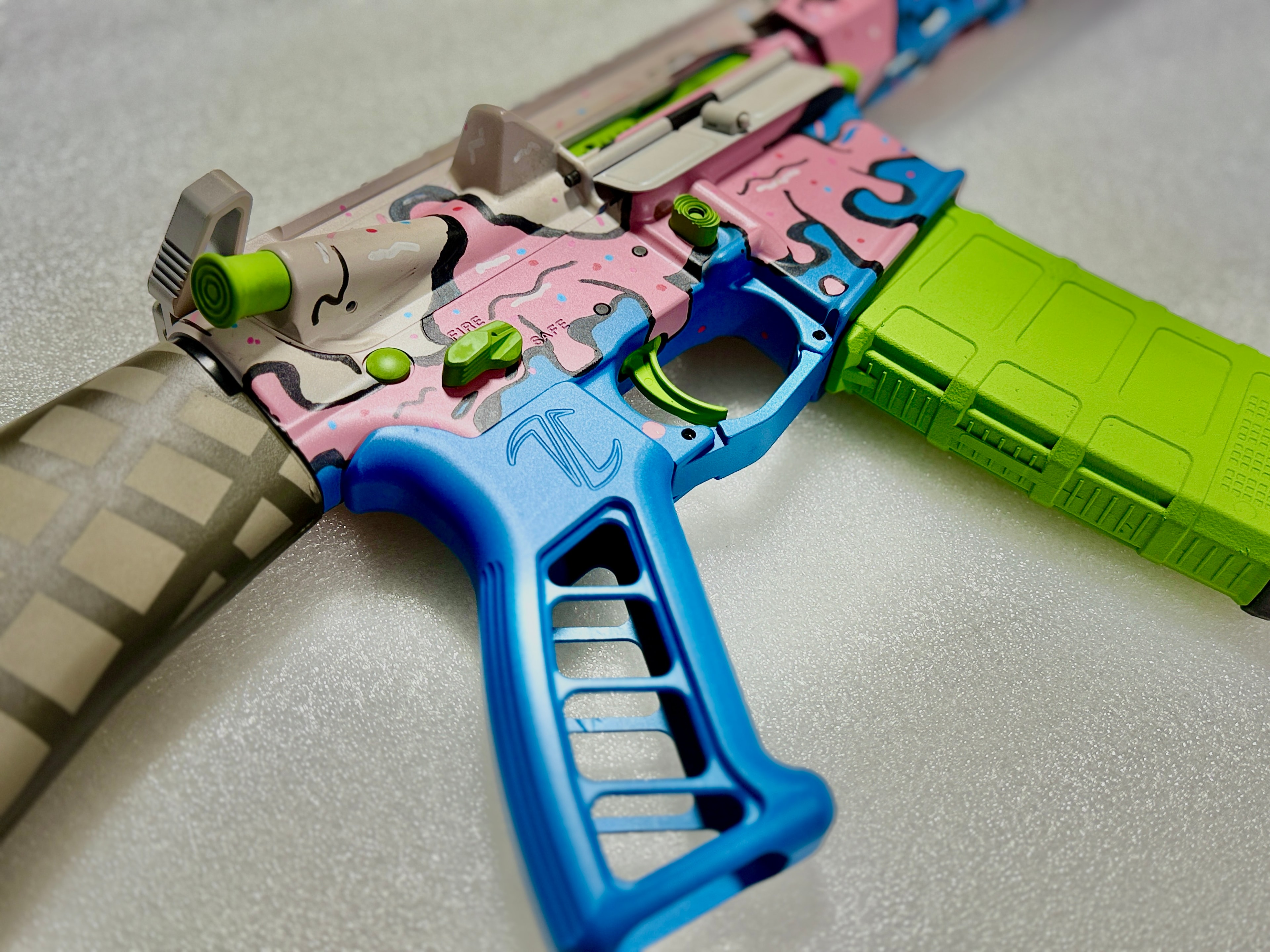 Custom multi-color Cerakote AR-15 lower receiver — pink, blue, lime green candy drip design by Northwoods Firearms
