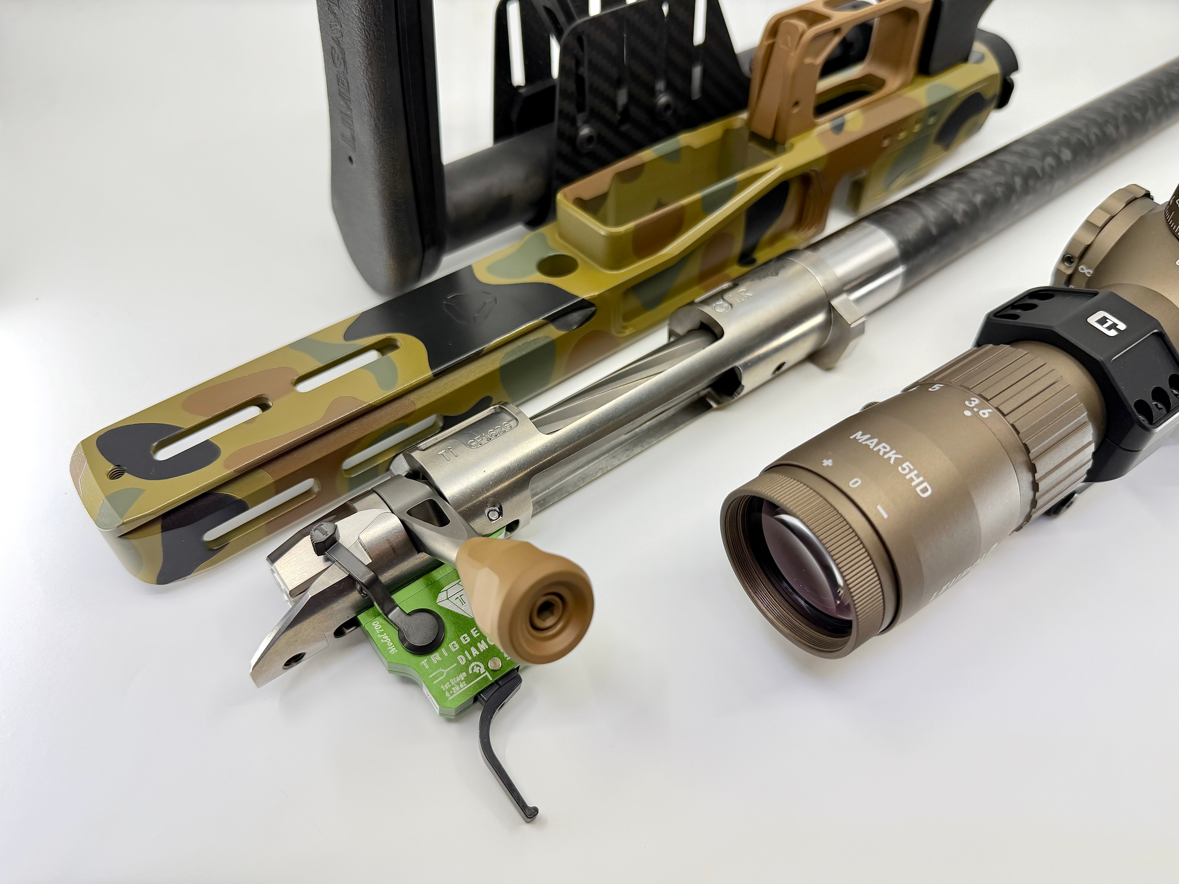 Detail shot of custom camo Cerakote precision rifle chassis with stainless barrel, Trigger Diamond trigger, and Nightforce Mark 5HD scope by Northwoods Firearms