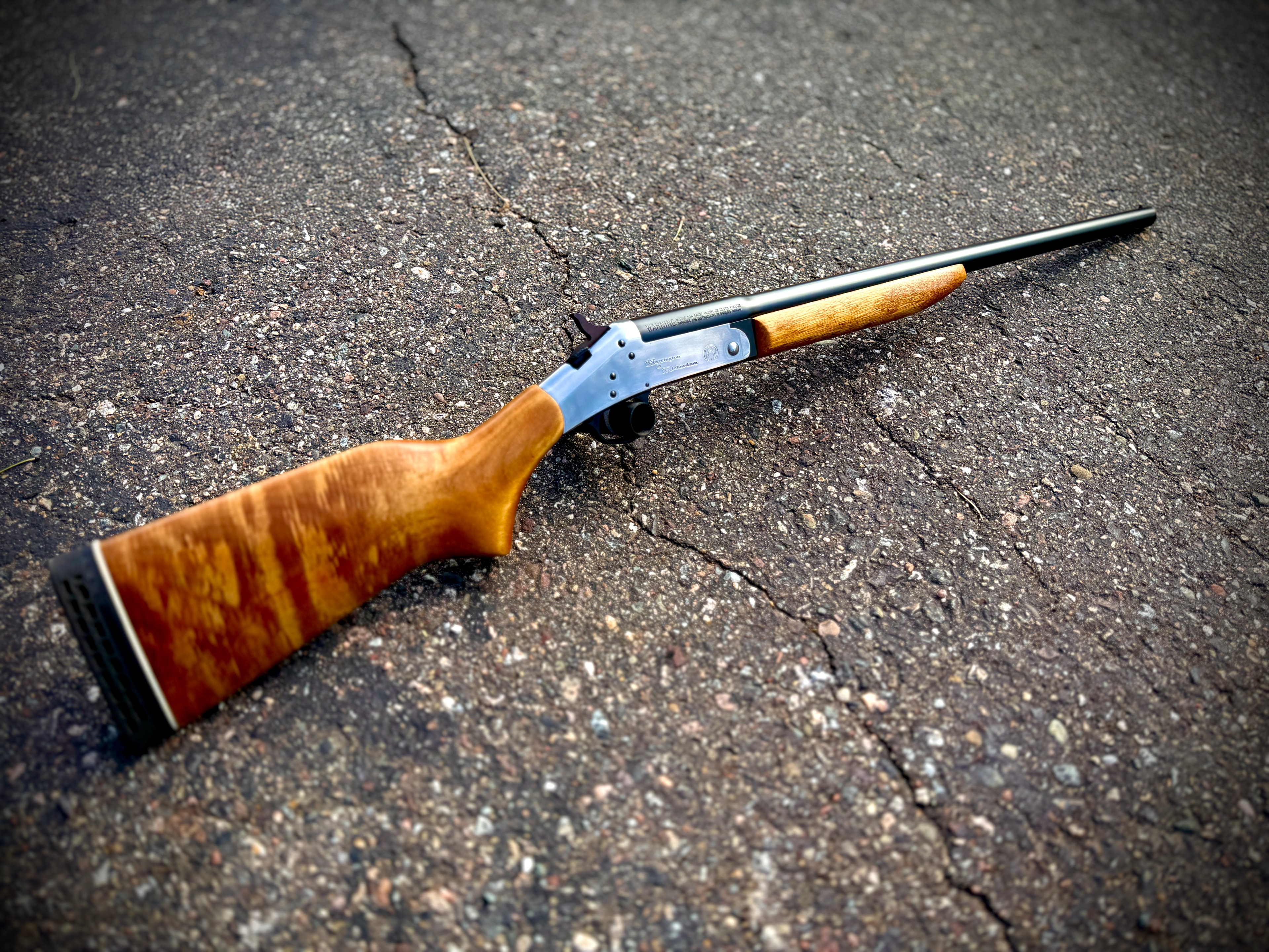 Browning single-shot shotgun with figured walnut stock and reblued receiver — full profile on pavement, custom work by Northwoods Firearms, Crandon, WI