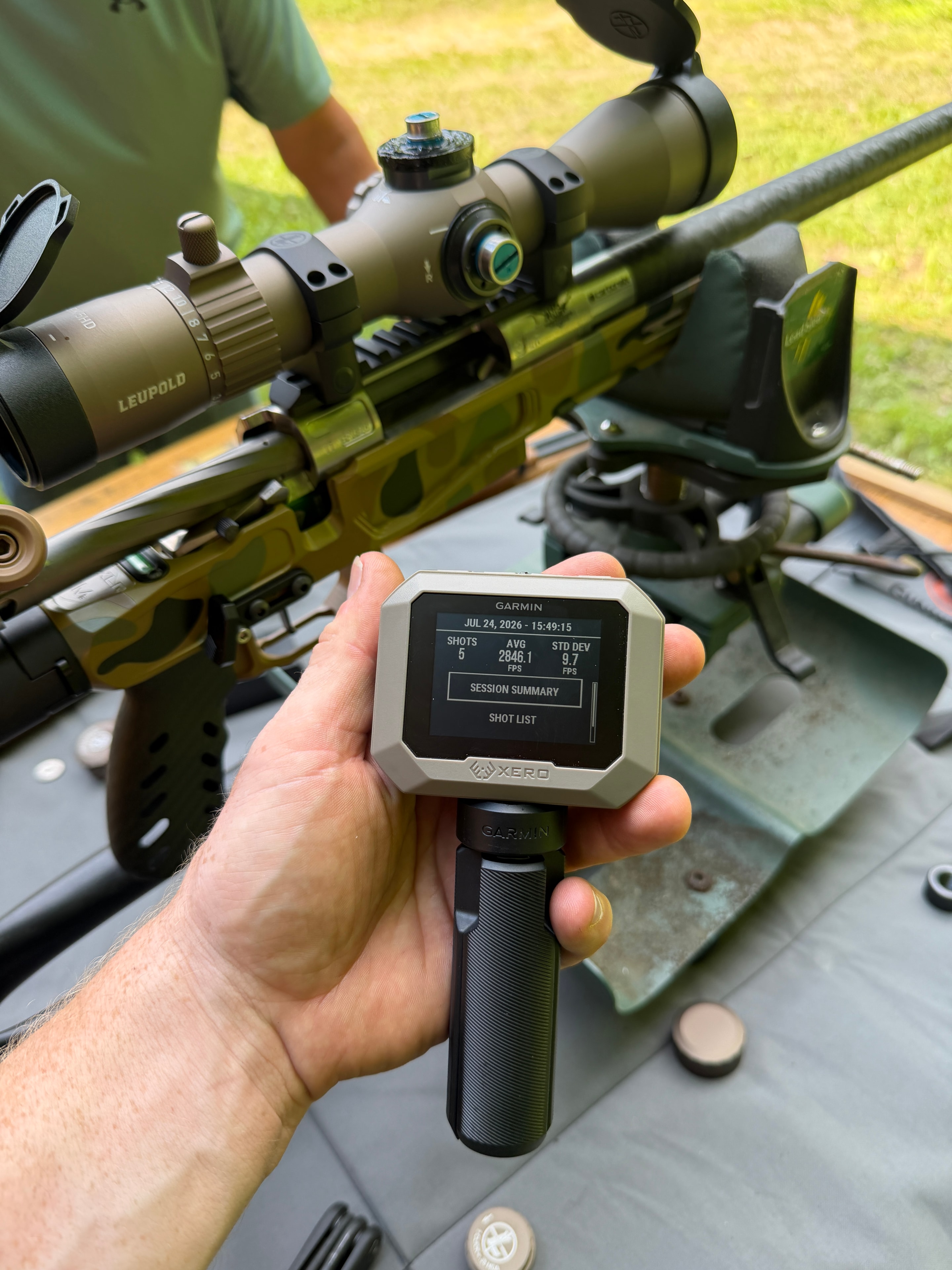 Precision camo rifle with Leupold scope and suppressor alongside a Garmin Xero chronograph showing 2846 FPS average — custom build testing at Northwoods Firearms