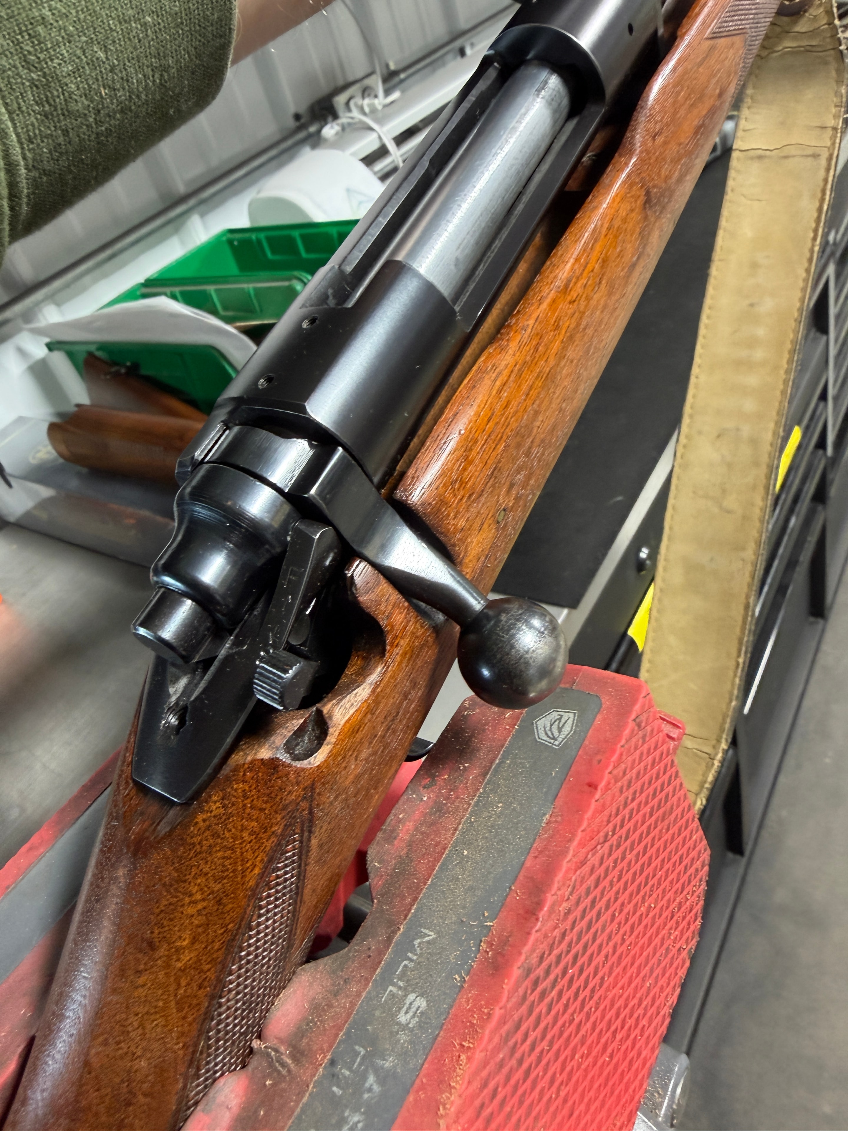 Vintage bolt-action rifle receiver and bolt handle detail — reblued action and refinished walnut stock in the Northwoods Firearms shop
