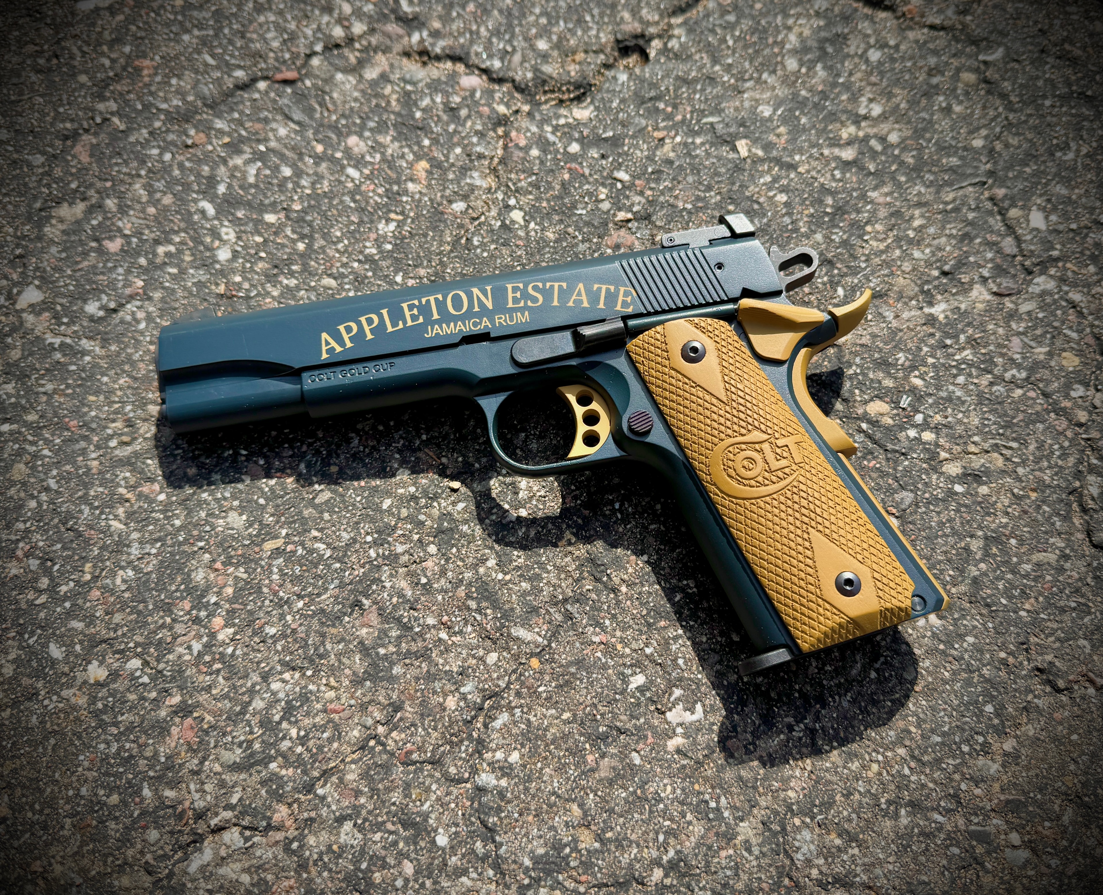 Laser-engraved Colt Gold Cup 1911 with Appleton Estate Jamaica Rum branding in gold lettering on blued slide, tan wood grips — by Northwoods Firearms