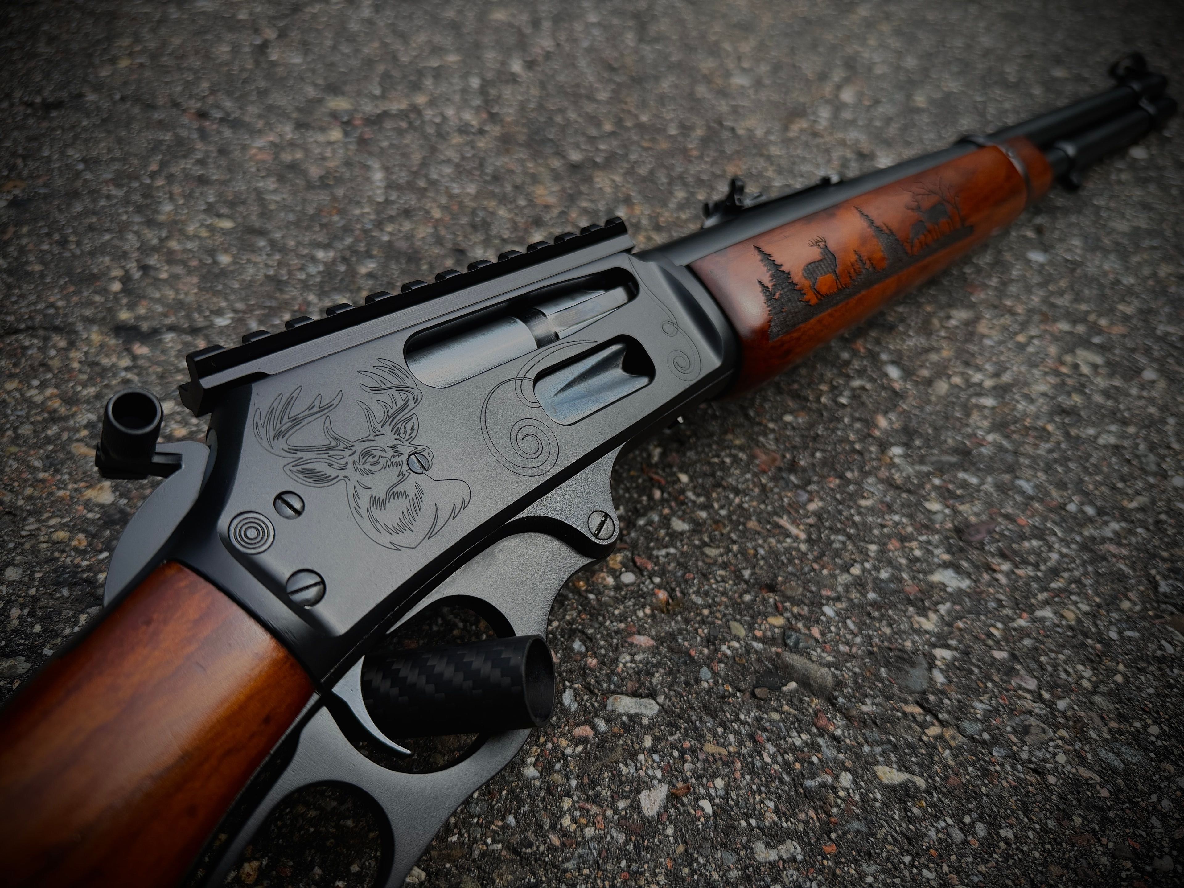 Close-up of laser-engraved whitetail buck and deer forest scene on Marlin lever-action receiver and walnut stock by Northwoods Firearms