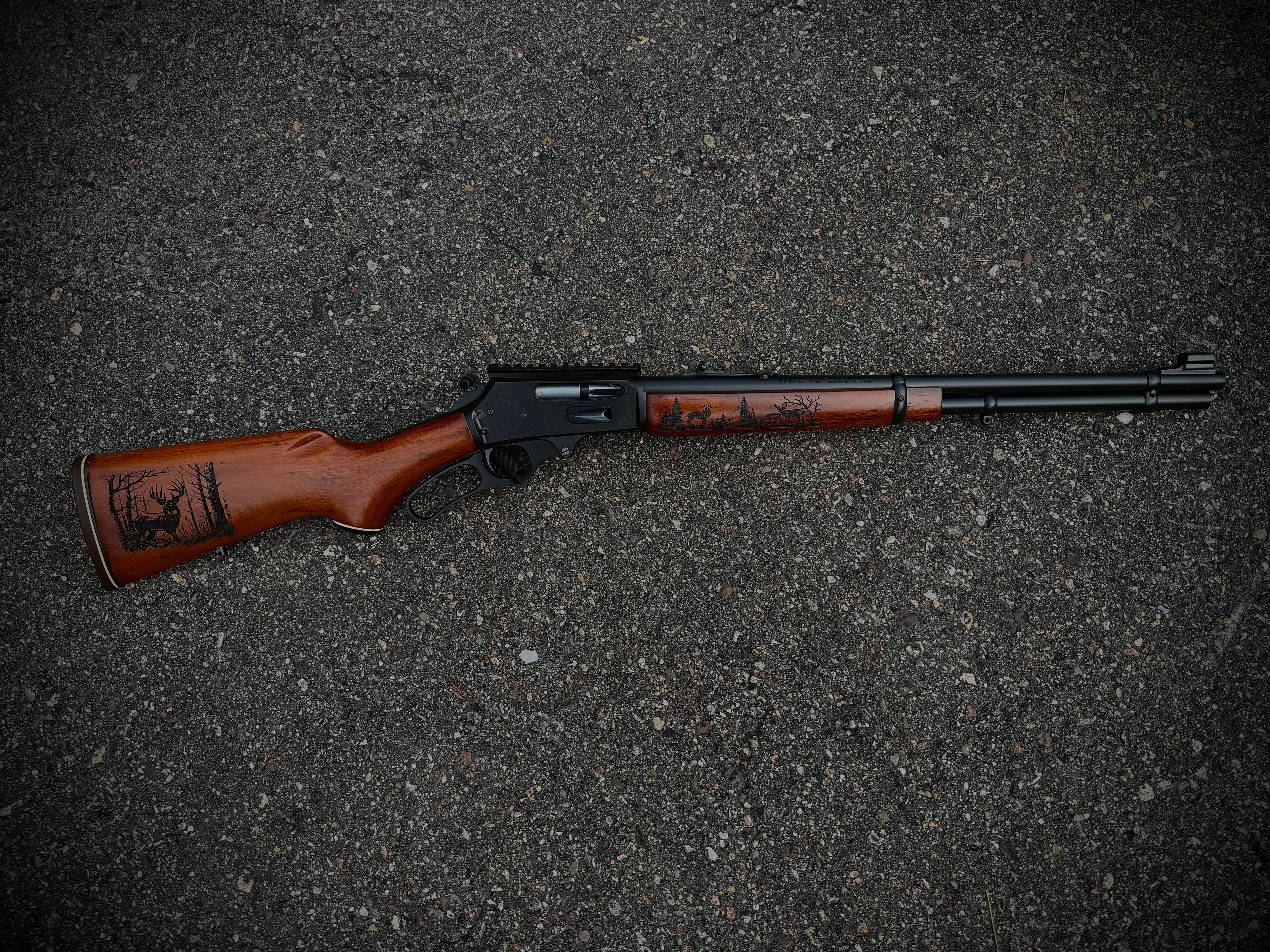 Full-length view of laser-engraved Marlin lever-action rifle with whitetail deer and pine tree scenes on walnut stock and forearm by Northwoods Firearms