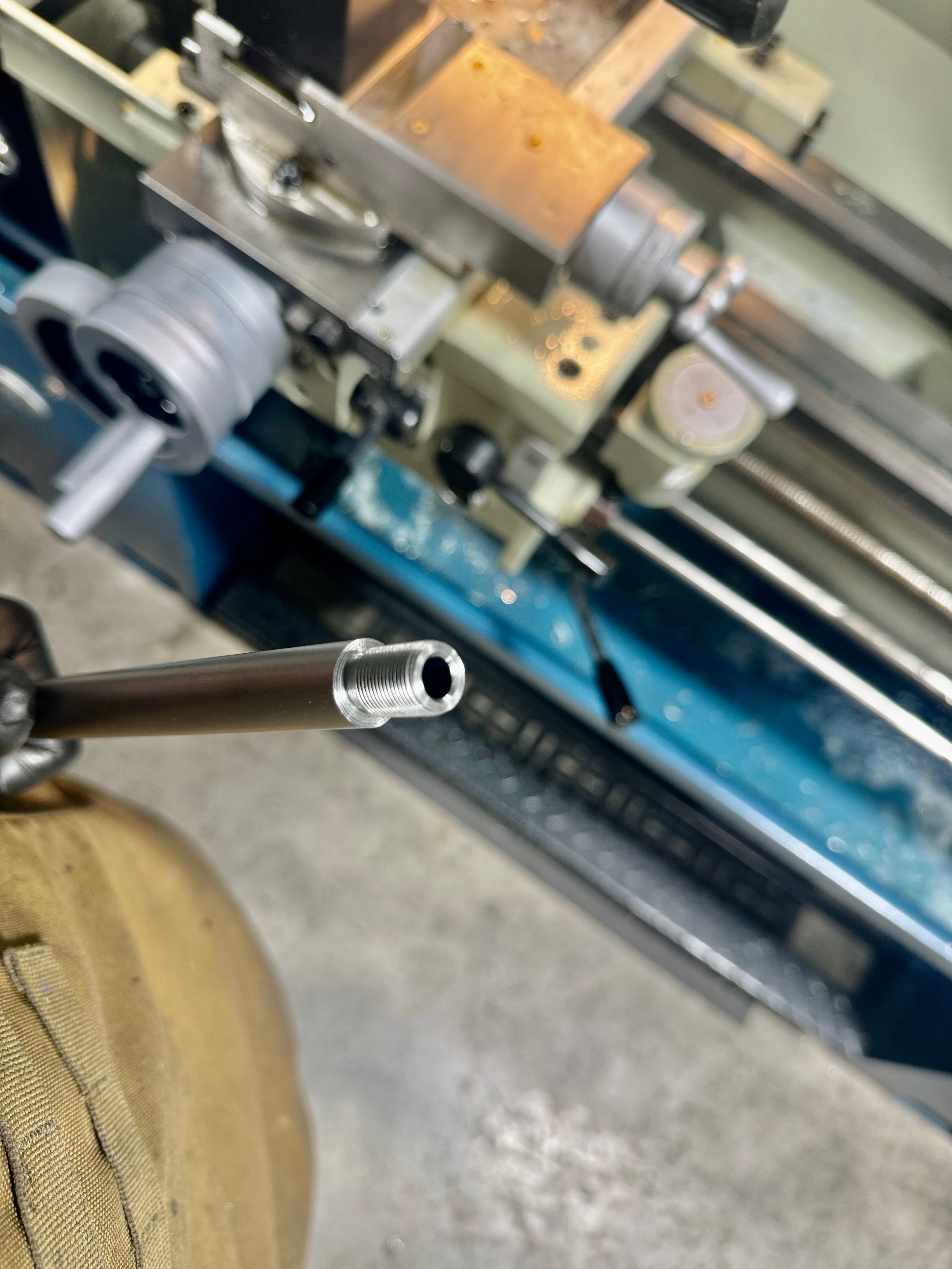 Freshly threaded rifle barrel muzzle on the Baileigh lathe at Northwoods Firearms — clean threads ready for suppressor or muzzle device