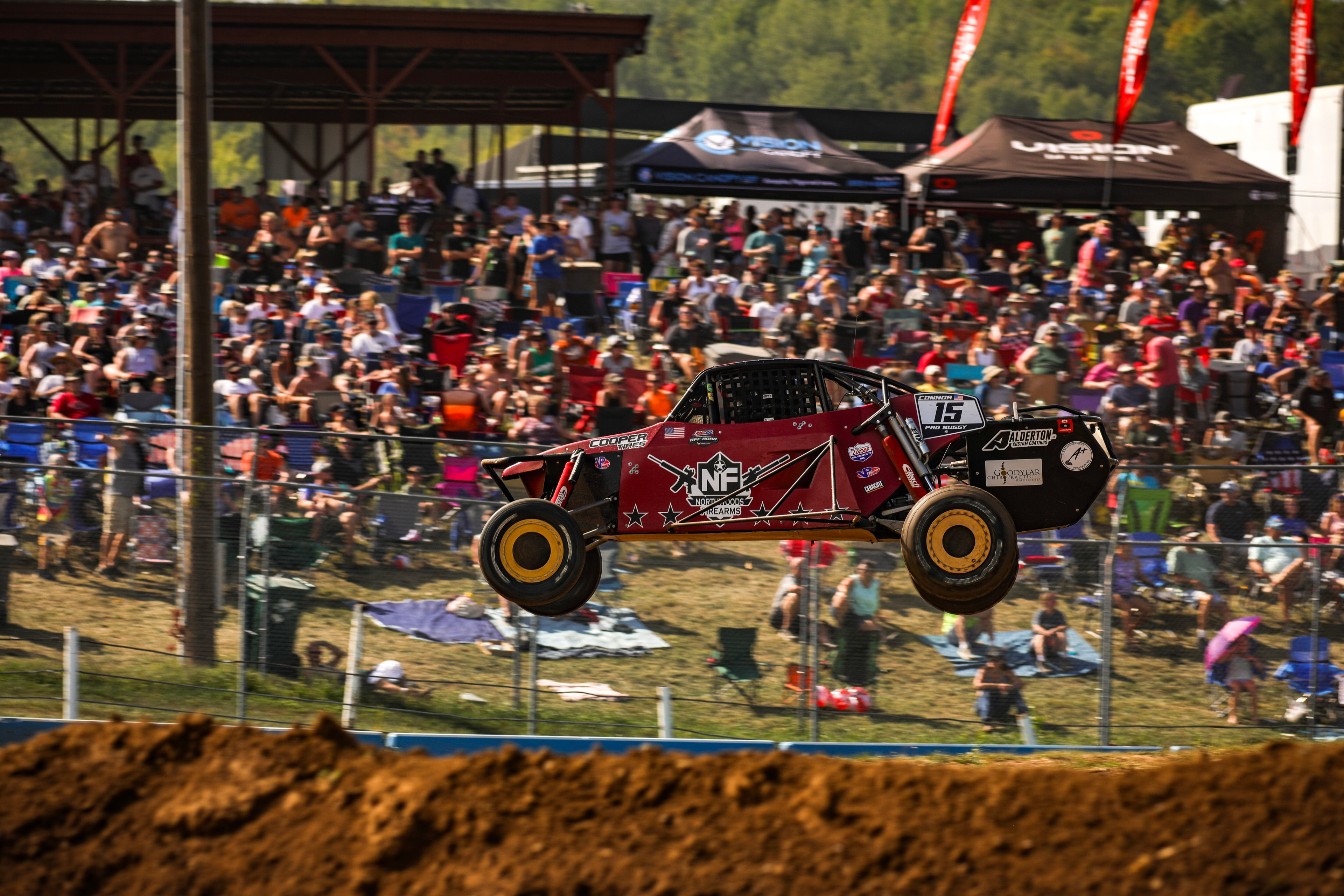 Connor #15 Northwoods Firearms Pro Buggy fully airborne in front of a massive crowd — Championship Off-Road Series