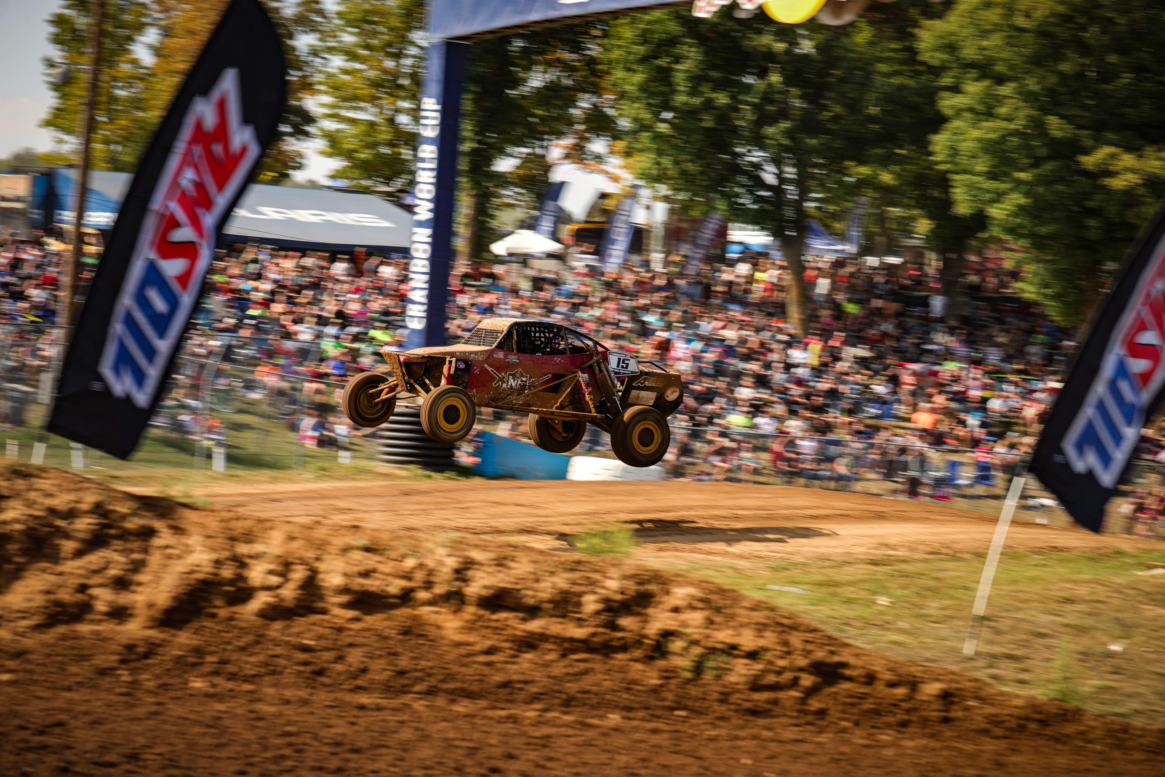 Connor #15 Northwoods Firearms Pro Buggy fully airborne at the Crandon World Cup in front of a sold-out crowd — AMSOIL banners visible