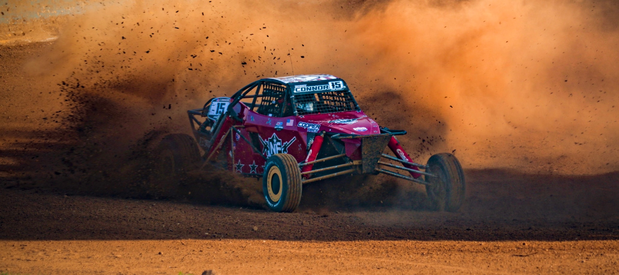 Connor #15 Northwoods Firearms Pro Buggy kicking up a massive orange dust cloud on the wide open dirt — Championship Off-Road Series
