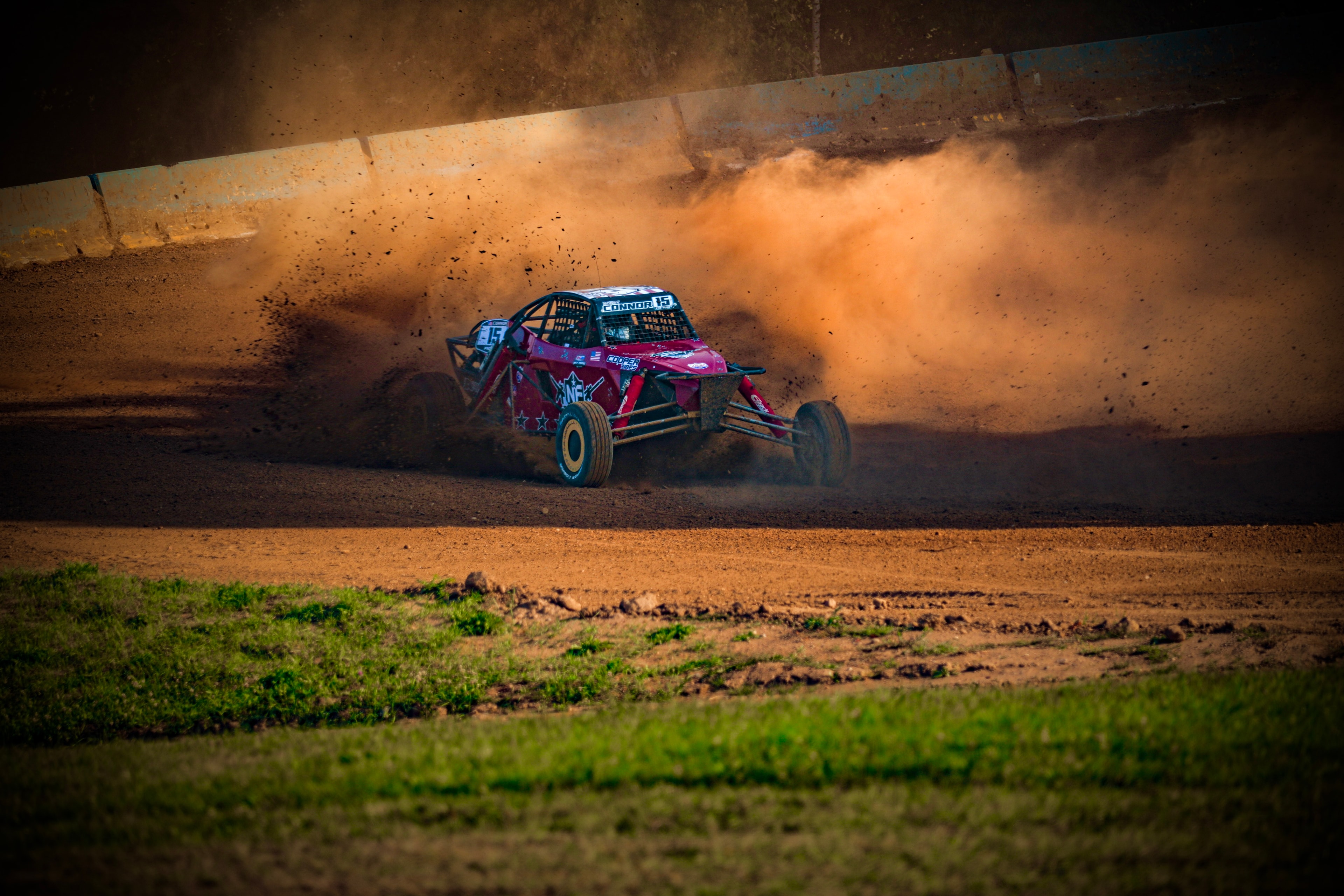 Connor #15 Northwoods Firearms Pro Buggy throwing a wall of dirt through a corner at sunset — Championship Off-Road Series