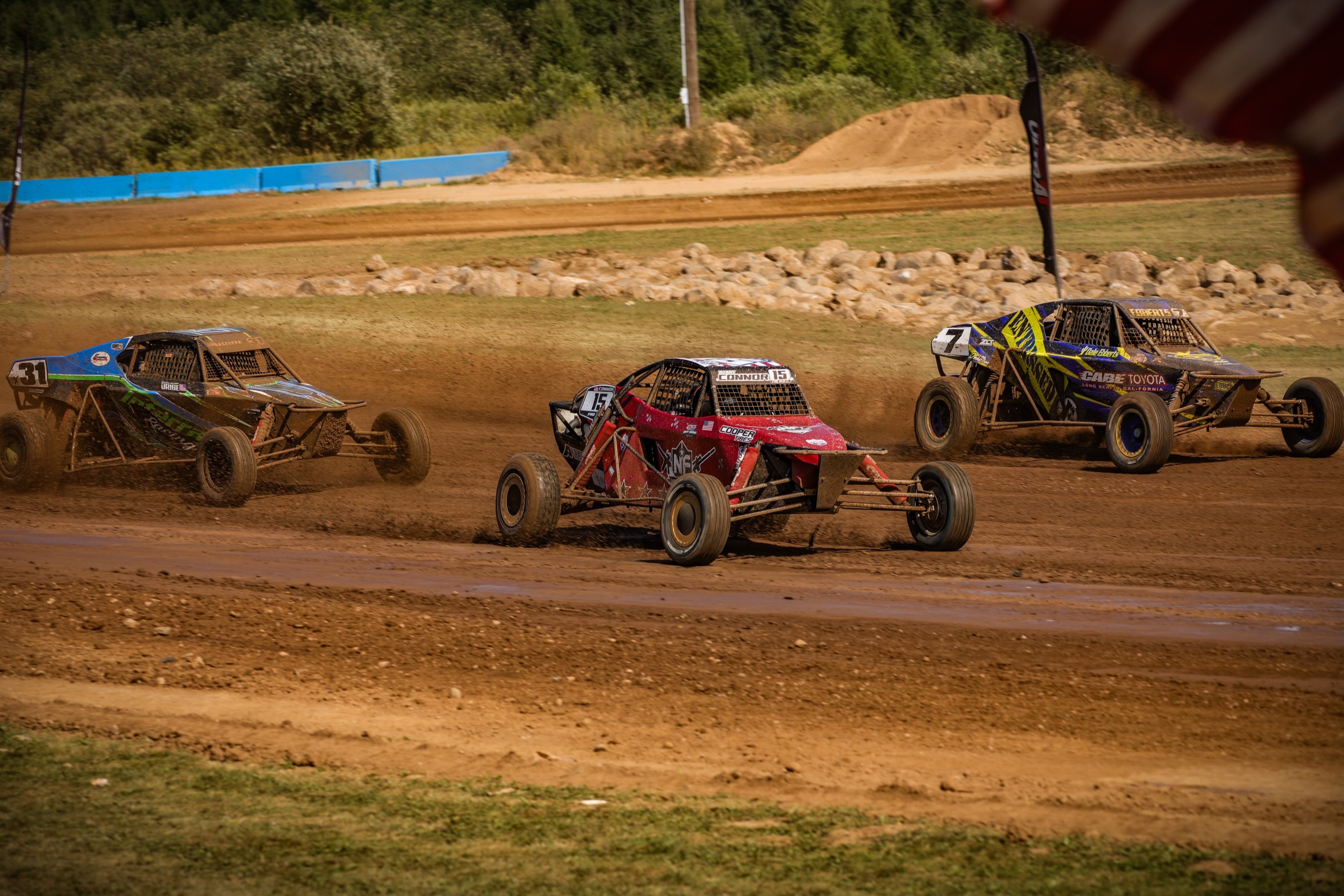 Connor #15 Northwoods Firearms Pro Buggy three-wide with #31 and #7 Cabe Toyota on the dirt — Championship Off-Road Series